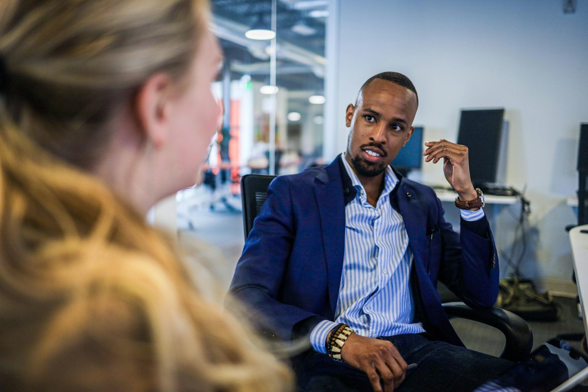 A professional in a navy blazer listening attentively during a one-on-one conversation.