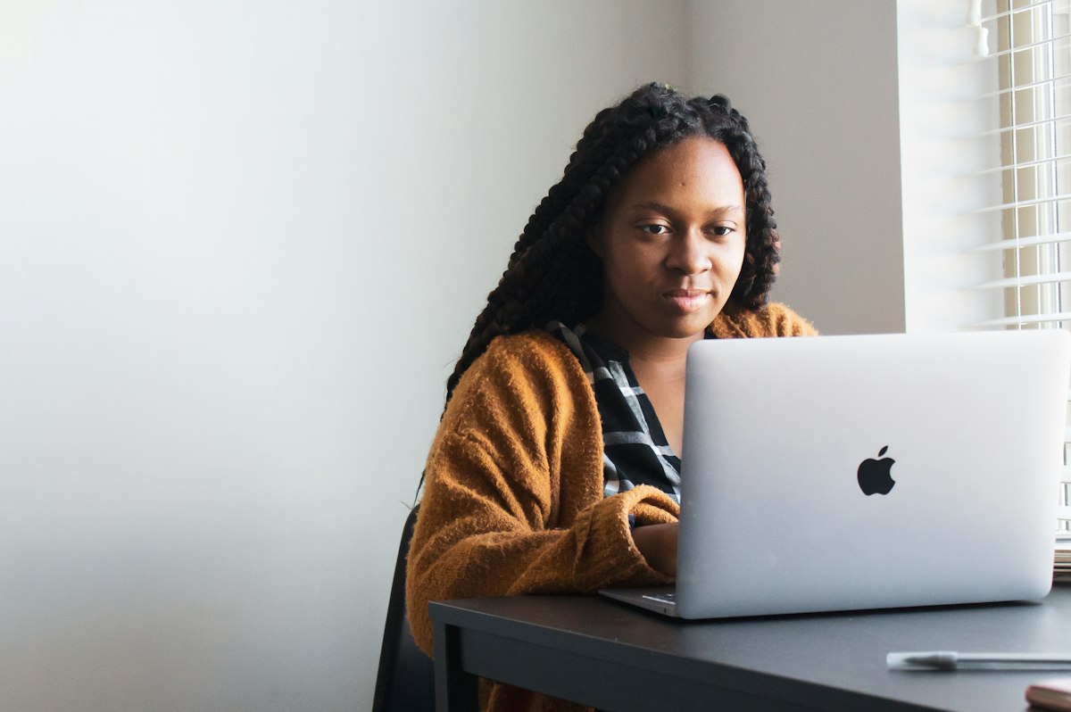 A woman at a laptop, looking toward the screen.